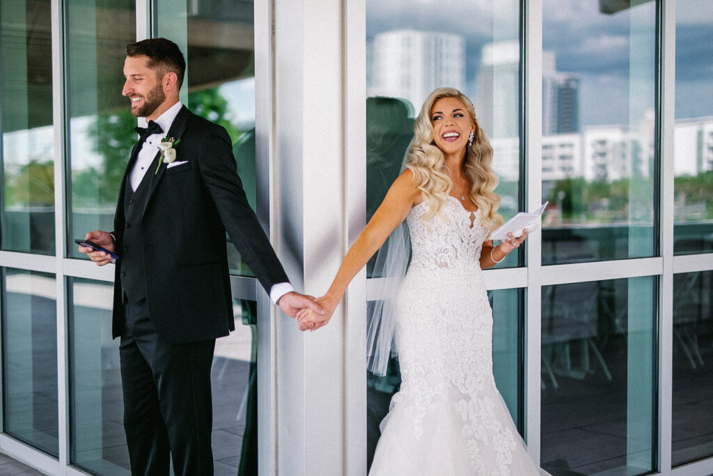 Elegant Modern Bride and Groom Holding Hands Without Seeing Each Other Unique First Look Portrait | Tampa Bay Wedding Hair and Makeup Femme Akoi Beauty Studio