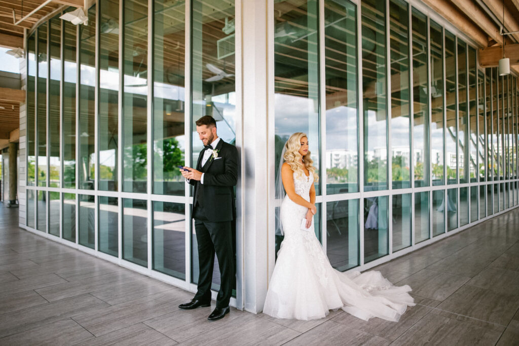 Elegant Modern Bride and Groom Hiding Behind Corners of Building Reading Letters from Each Other Without Seeing Each Other Unique First Look Portrait | Tampa Bay Wedding Hair and Makeup Femme Akoi Beauty Studio