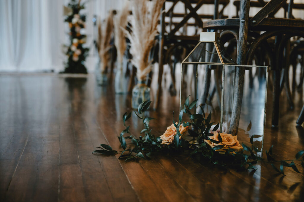 Gold Lanterns with Floral and Greenery Details and Pampas Leaves in Clear Vases | Wedding Ceremony Bohemian Aisle Décor