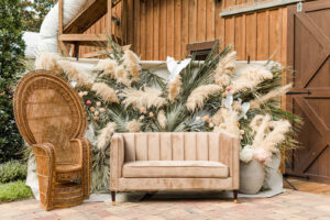 Boho Mid-Century Modern Wedding Decor, Camel Velvet Tufted Loveseat, Grand Peacock Rattan Chair, Palm Fronds and Pampas Grass Backdrop | Florida Wedding Venue Mision Lago Estates | Tampa Chair Rentals Kate Ryan Event Rentals | | Registration Table Entrance Central Florida Wedding Planner Stephany Perry Events | Big Fake Wedding