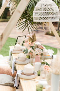 Boho Mid-Century Modern Wedding Decor, Natural Wood Low Picnic Table, Plates with Personalized Coconuts, Wicker White Lamp Shade, Dried Leaves and Blush Pink Roses | Tampa Bay Table Rentals Kate Ryan Event Rentals | Head Table Design Something Blue Orlando | Big Fake Wedding