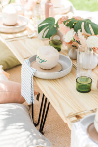 Boho Mid-Century Modern Wedding Decor, Natural Wood Low Picnic Table, Plates with Personalized Coconuts, Wicker White Lamp Shade, Dried Leaves and Blush Pink Roses | Tampa Bay Table Rentals Kate Ryan Event Rentals | Head Table Design Coastal Coordinating | Big Fake Wedding