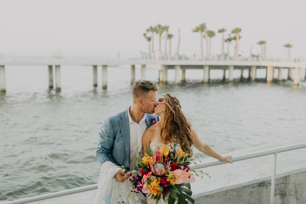 Intimate Bride and Groom Kissing Waterfront Wedding Photo | Tropical Colorful Floral Bouquet, King Protea, Orange Flowers, Pink Anthurium, Monstera Palm Leaf | Tampa Bay Wedding Photographer Amber McWhorter Photography