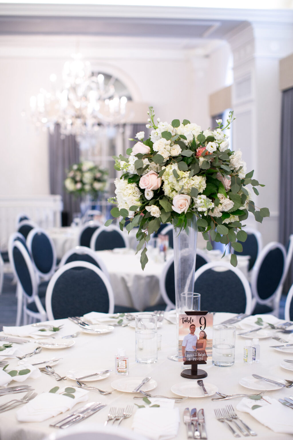 Elegant Wedding Reception Tablescapes with Navy and Silver Chairs and White Linens | Tall Floral Centerpieces in a Clear Vase
