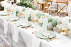 Boho Mid-Century Modern Wedding Reception Decor, Long Table with Sage Green, Gray and White Balloon Garland, Sage Green Plates, Dried Leaves, Gold Flatware, Acrylic Chairs, Modo Wine Glasses | Table Design Weddings by Abi | SoPoppin' Balloons | Tampa Bay Chair and Table Rental Kate Ryan Event Rentals | Big Fake Wedding |