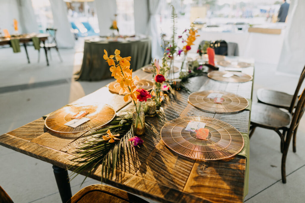 Tropical Boho Tent Wedding Reception Decor, Long Wooden Feasting Table with Bamboo Chargers, Palm Fronds Garland, Single Flowers in Small Vases | Tampa Bay Wedding Photographer Amber McWhorter Photography | Wedding Rentals Kate Ryan Event Rentals