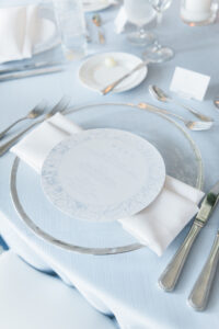 Circular White and Blue Wedding Menu Place Setting on Silver Rimmed Glass Charger Plate | Gabro Event Services