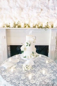 Blue and White Floral Lace Linens on Wedding Sweetheart Table | Parties A'La Carte | White Three Tiered Round Wedding Cake with White Roses and Greenery