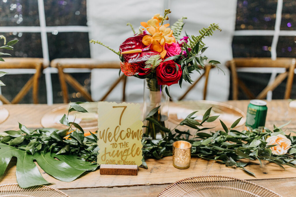 Tropical Boho Wedding Reception Decor, Red Roses, Yellow Orchid, Red Anthurium, Greenery Floral Centerpiece, Greenery Table Runner Garland, Acrylic and Sage Green with Gold Table Number | Tampa Bay Wedding Photographer Amber McWhorter Photography | Wedding Rentals Kate Ryan Event Rentals