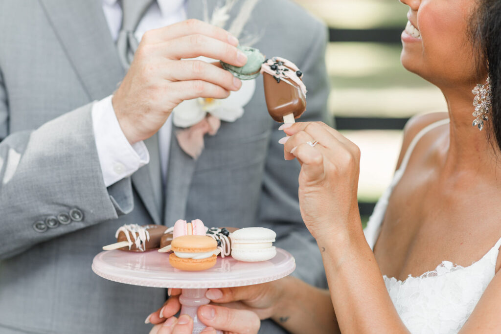 Florida Bride and Groom Cheering with Mini Desserts Holding Tray of Macaroos and Cakesicles | Big Fake Wedding Tampa