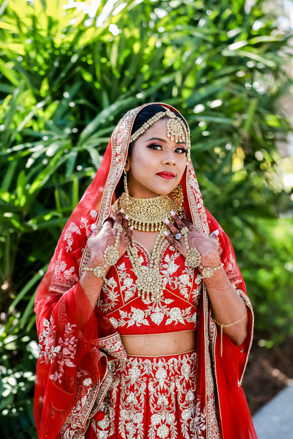 Indian Hindu Bride Wearing Red and Gold Lengha Two Piece Dress and Veil with Elaborate Jewelry, Gold Choker, Headpiece and Dangle Earrings, Henna Tattoo Hands | Tampa Bay Wedding Photographer Lifelong Photography Studios