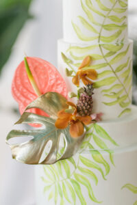 Five Tier White and Green Palm Leave Painted Wedding Cake Decorated with Pink Anthurium, Gold Painted Monstera Leaf, Mini Pineapple, Pink Pin Cushion Flower Cake Topper | Tampa Bay Wedding Planner Eventfull Weddings