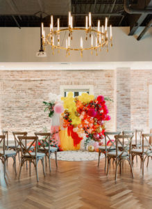 Colorful Whimsical Wedding Ceremony Decor, Wooden Cross Back Chairs, Yellow, Orange, Pink, Gold Balloon Fringe Ceremony Backdrop | Downtown St Pete Modern Industrial Chic Wedding Venue Red Mesa Events | Tampa Bay Wedding Photographer Dewitt for Love | Wedding Chair Rentals Kate Ryan Event Rentals