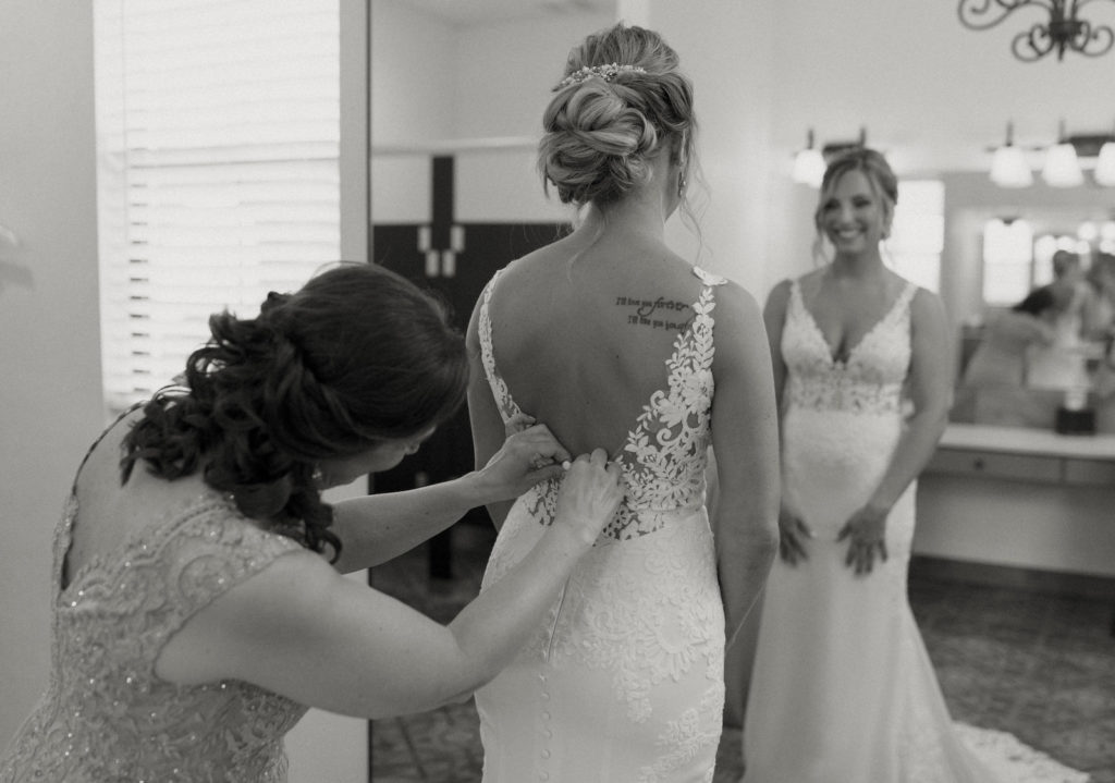 Mother of the Bride Helping the Bride Get Ready Black and White Portrait | Low Back Button Back Lace Fitted Wedding Dress | Laura Jacobs Bridal, Stella York