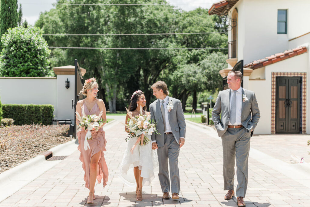 Boho Bride Wearing High Low Skirt Wedding Dress Holding Wild Floral Bouquet with Calla Lily and Pampas Grass, Groom and Groomsman in Gray Suit, Bridesmaids in Mauve Pink Ruffle Dress | Tampa Wedding Venue Mision Lago Estates | Big Fake Wedding