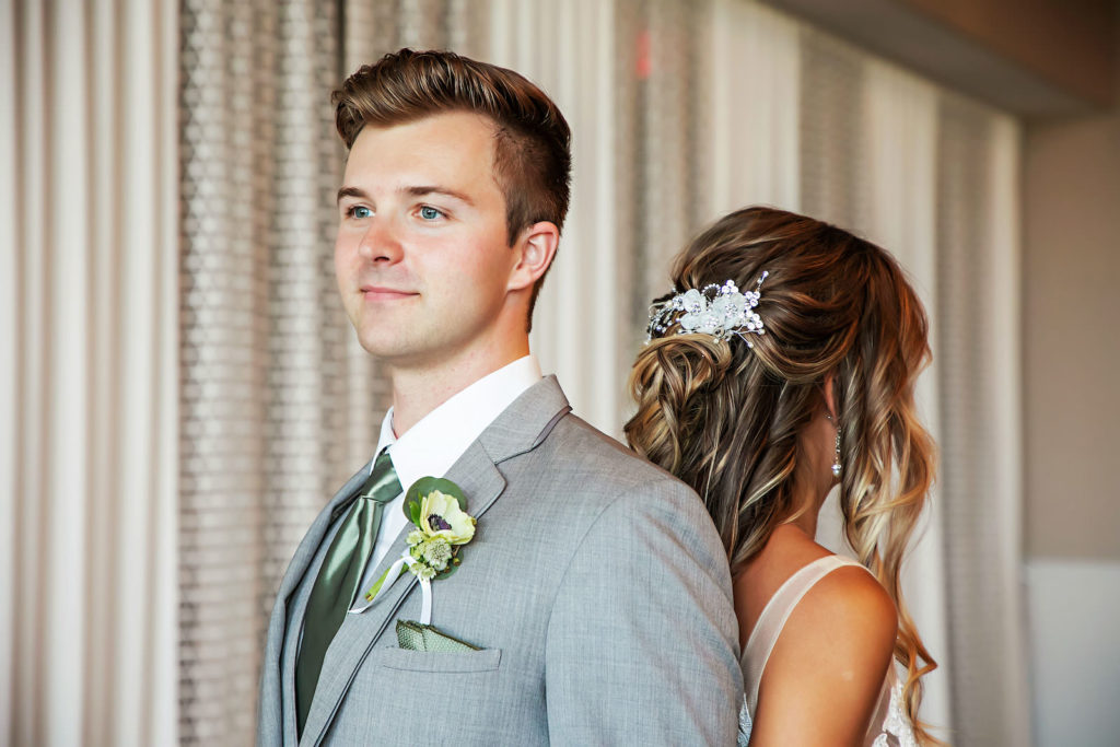 Bride and Groom Back to Back First Look Portrait | Groom Wearing Gray Suit with Sage Green Tie and Pocket Napkin, White Anemone Flower Boutonniere | Tampa Bay Wedding Photographer Limelight Photography | Wedding Hair and Makeup Adore Bridal | Wedding Florist Beneva Florals