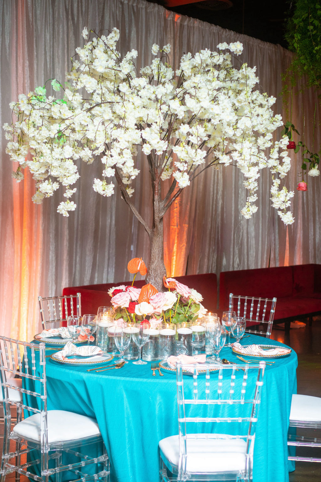 Modern Reception Decor, Round Table with Elaborate Centerpiece, Tall Tree with White Flowers Towering Over Aqua Blue Linens and Ghost Chiavari Chairs
