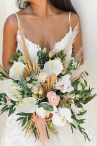 Boho Bride Wearing Lace and Spaghetti Strap V Neckline Wedding Dress with Braided Crown and Pink Flower Crown Holding Wild Floral Bouquet, Pampas Grass, White Calla Lily, Blush Pink Roses, Greenery, Eucalyptus, Dried Leaves | Tampa Big Fake Wedding