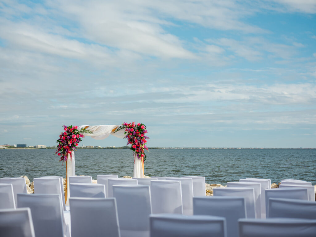 Beach Waterfront Wedding Ceremony Decor, Arch with White Linen Draping, Jewel Tone Pink and Purple Floral Arrangement | Tampa Bay Wedding Planner Perfecting the Plan | Wedding Florist Iza's Flowers | Wedding Venue The Current Hotel Tampa