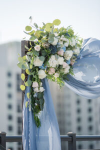 Wooden Wedding Arch with Dusty Blue Draping and Blue, White Florals, with Greenery Detail