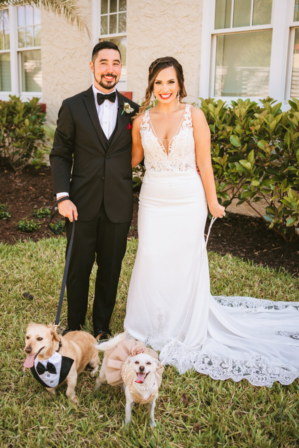 Florida bride wearing floral lace and illusion plunging v neckline fitted wedding dress, groom wearing black tuxedo with dogs dressed up | Tampa wedding photographer Bonnie Newman Creative | Wedding hair and makeup Femme Akoi Beauty Studio