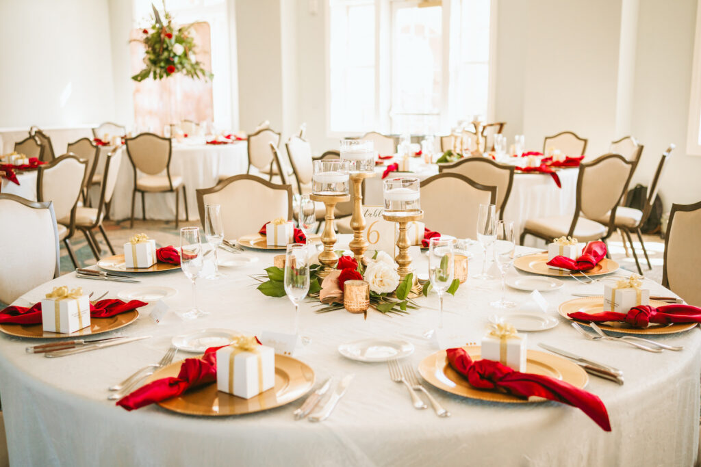Fall classic wedding reception decor, gold chargers with red linen napkins, wedding favor box, gold candlestick floating candles centerpiece | Tampa Bay wedding photographer Bonnie Newman Creative | Wedding planner Coastal Coordinating