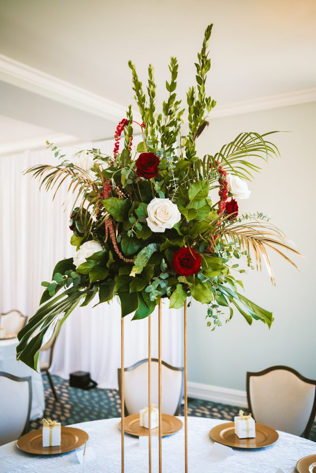 Fall wedding reception decor, tall gold stand with burgundy red and white roses, hanging amaranthus, palm fronds, greenery floral centerpiece | Tampa wedding photographer Bonnie Newman Creative | Wedding planner Coastal Coordinating | Wedding florist Iza’s Flowers