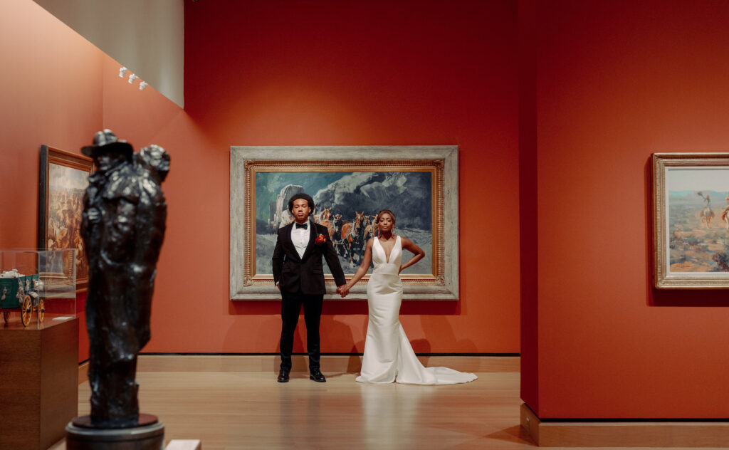 Modern Bride Wearing Sleek Plunging Neckline Wedding Dress and Pink Tassel Earrings, Groom Wearing Black Tuxedo Inside Art Gallery at St. Pete Wedding Venue The James Museum | Tampa Wedding Photographer Dewitt for Love