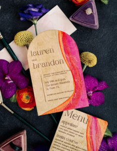 Colorful Art Inspired Wooden Stationery, Wooden Wedding Invitation Painted with Pink and Orange Whimsical Curves, Wooden Invitation Painted with Pink and Orange, Wedding Engagement Ring in Triangular Purple Velvet Ring Box, Black Groom Wedding Ring in Mauve Triangular Wedding Ring Box | Tampa Bay Wedding Photographer Dewitt for Love | Wedding Planner Wilder Mind Events
