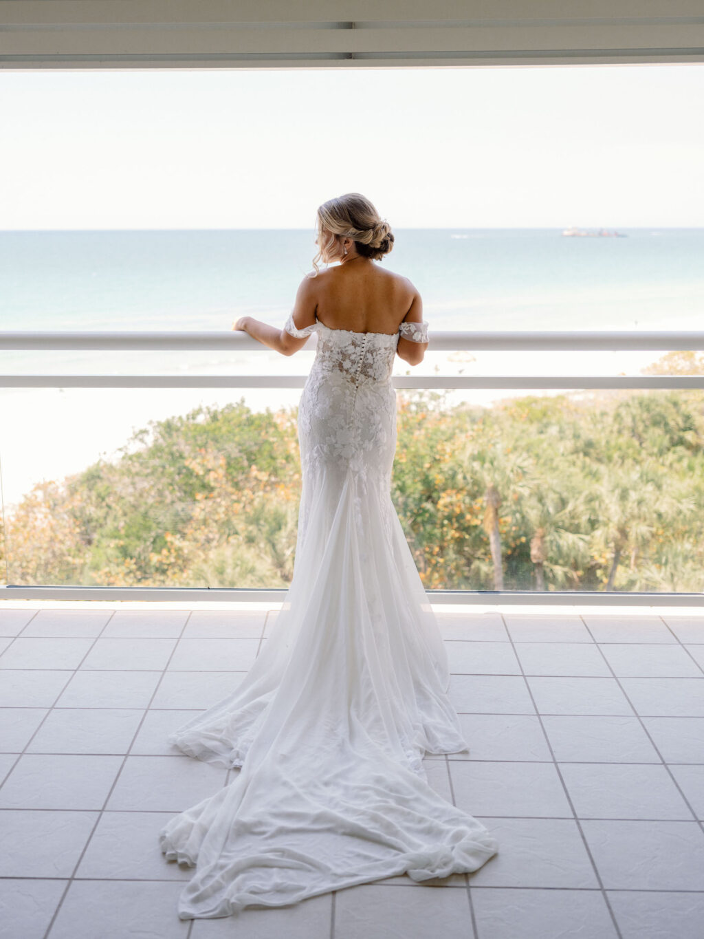 Florida Bride Getting Ready Overlooking Balcony of Gulf of Mexico, Wearing Provinias Wedding Dress with Floral Off the Shoulder Sleeves | Sarasota Wedding Venue The Resort at Longboat Key Club