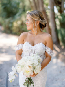 Florida Bride Wearing Provinias Wedding Dress with Floral Applique Off the Shoulder Sleeves with Sweetheart Neckline, Braided Updo, Luxurious Round Ivory Floral Bouquet with Orchids