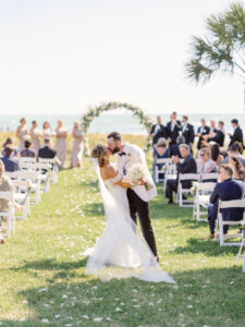 Waterfront Wedding Ceremony, Bride and Groom Kiss at Processional, Modern Circle Floral Arch with Classic White and Greenery Florals | Sarasota Wedding Venue The Resort at Longboat Key Club | South Beach Lawn