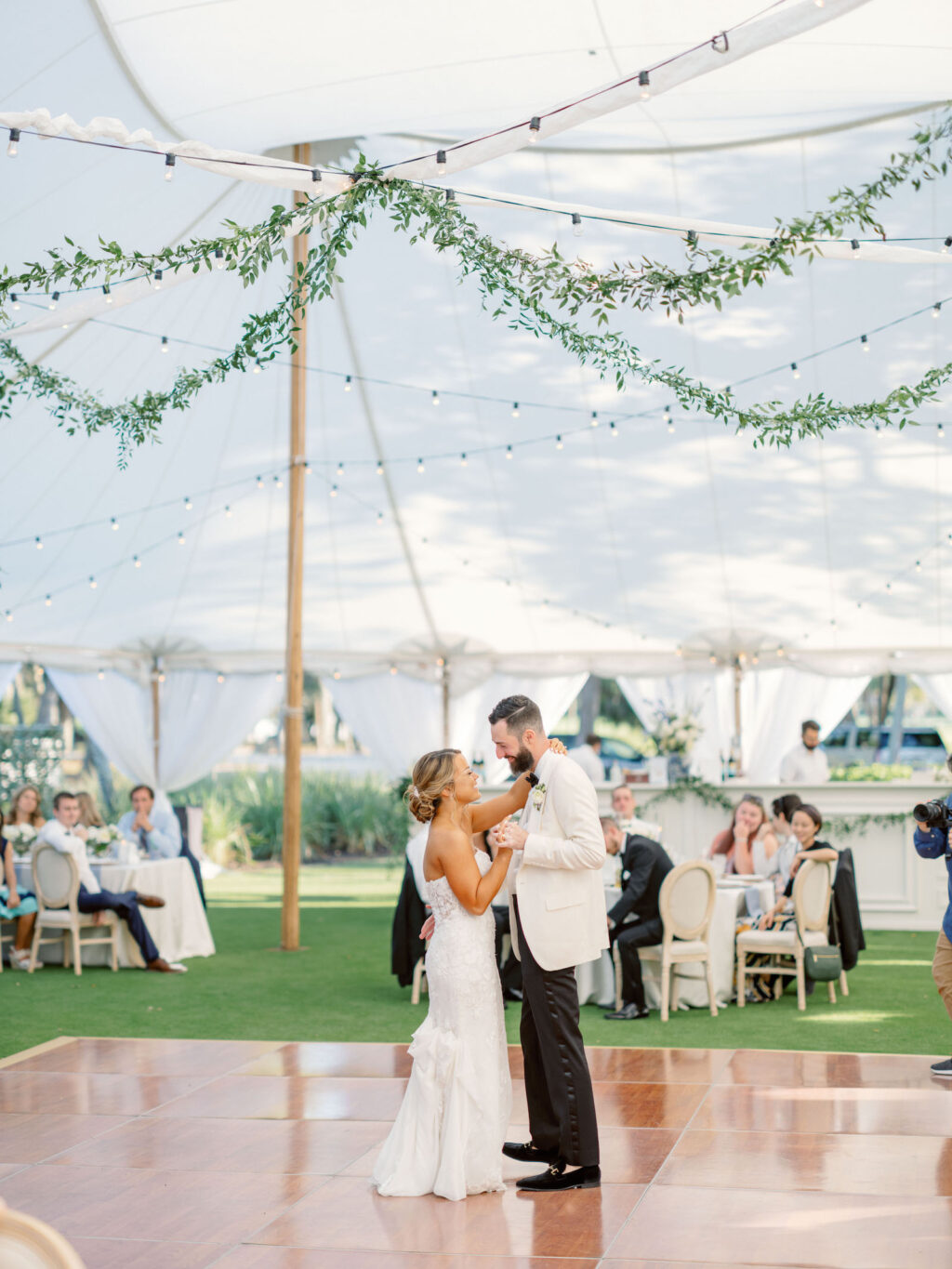 Sarasota Bride and Groom First Dance in Sperry Tented Garden Reception with Market Lighting and Hanging Greenery | Florida Wedding Venue The Resort at Longboat Key Club | South Harbourside Lawn