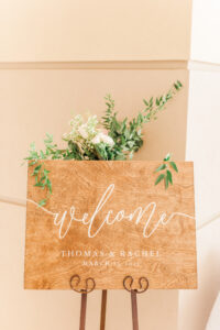 Romantic Pink St. Pete Garden Wedding Ceremony Decor | Wooden Welcome Sign with Greenery and Ivory Floral Arrangement | Tampa Bay Wedding Florist Brides N Blooms Designs