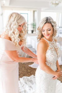 Romantic Pink Wedding | Mom Helping Bride Put on Lace Applique and Illusion Halter Wedding Dress