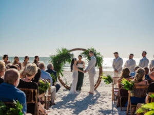 St. Pete Beach Bride and Groom Exchange Vow, Tropical Inspired Wooden Circle Arch with Greenery Flora | Florida Beach Wedding Ceremony