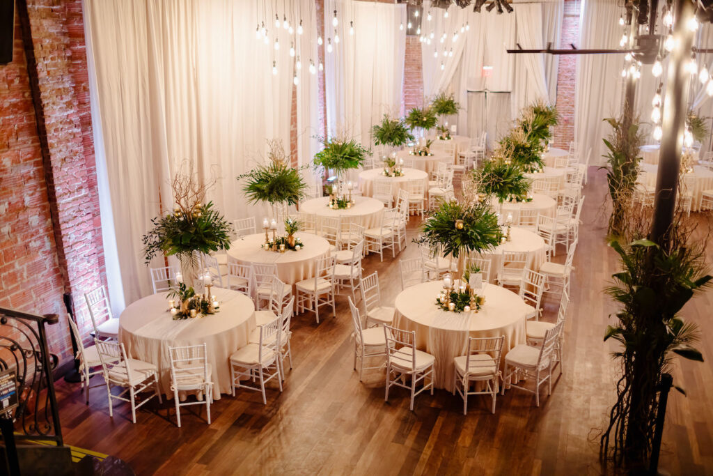 Tropical Elegant Wedding Reception and Decor, Round Tables with Champagne Linens and Tall Centerpieces with Greenery and Palm Leafs, White Chiavari Chairs | Seated 125 Guest Count at Historic Florida Wedding Venue NOVA 535