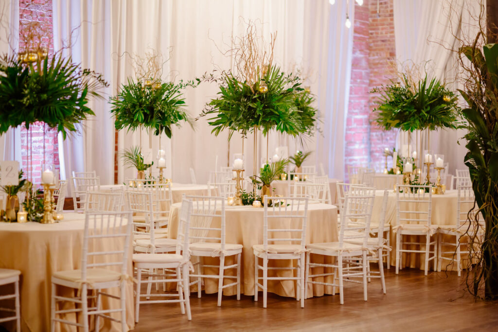 Tropical Elegant Wedding Reception and Decor, Round Tables with Champagne Linens and Tall Centerpieces with Greenery and Palm Leafs, White Chiavari Chairs, Gold Candle Sticks and Pineapples | Florida Wedding Venue NOVA 535 in Downtown St. Pete