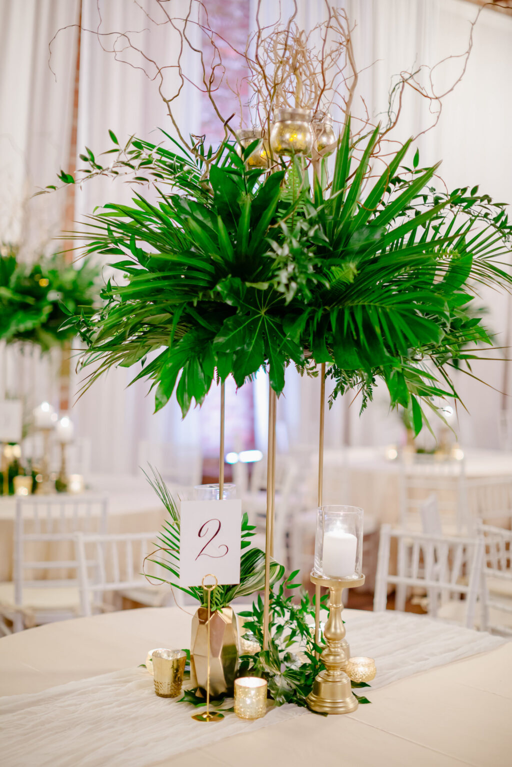 Tropical Elegant Florida Wedding Reception and Decor, Round Tables with Champagne Linens and Tall Centerpieces with Greenery and Palm Leafs, White Chiavari Chairs, Gold Candle Sticks and Pineapples