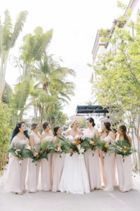 Tropical Pink and Green Wedding, Bride with Bridesmaids in Mix and Match Blush Pink Dresses Holding Tropical Floral Bouquets | St. Pete Waterfront Wedding Venue The Vault | Tampa Bay Wedding Hair and Makeup Savannah Olivia Beauty | Lemon Drops Floral