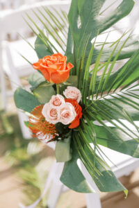 Tropical Pink and Green Wedding Ceremony Decor, Monstera and Palm Frond Leaves, Blush Pink and Orange Roses, Pin Cushion Protea Floral Arrangement on Chair | Tampa Bay Wedding Planner Coastal Coordinating | Lemon Drops Floral