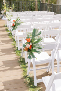 Tropical Pink and Green Wedding Ceremony Decor, Monstera and Palm Frond Leaves, Blush Pink and Orange Roses, Pin Cushion Protea Floral Arrangement on Chair | Tampa Bay Wedding Planner Coastal Coordinating