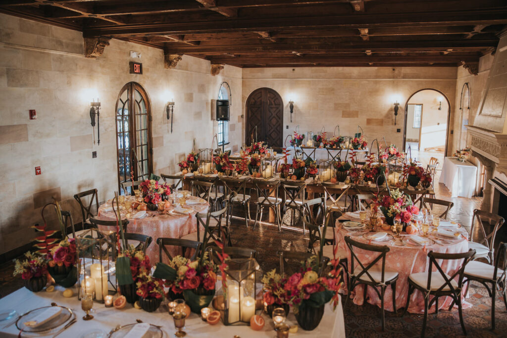 Indoor Tuscan Sarasota Wedding Reception with Wooden Chairs and Pink and Orange Floral Tablescapes | Sarasota Wedding Planner MDP Events