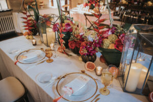 Moody Tablescapes with Clear Plating with Gold Trim and Pink and Orange Floral Centerpieces | Candle and Fruit Wedding Decor | Sarasota Wedding Planner MDP Events