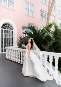 Florida Bride Wearing A-Line Classic Wedding Dress with Full Length Veil Blowing Outside of St. Petersburg Pink Palace The Don CeSar Hotel