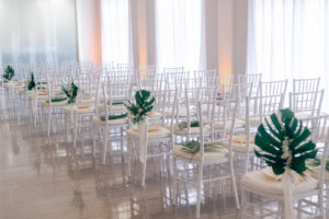 White and Green Modern Minimalist Tropical Wedding Ceremony Decor, White Chiavari Chairs with Palm Fronds and Monstera Palm Leaves and White Flower Arrangements | Tampa Bay Wedding Planner Taylored Affairs | Downtown Tampa Wedding Venue The Vault