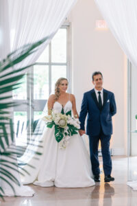 White and Green Modern Minimalist Tropical Wedding Ceremony, Bride Holding Lush White Orchid, King Protea, Roses, Anthurium and Monstera Palm Leaves Floral Bouquet with Dad Walking Down the Wedding Ceremony Aisle | Tampa Bay Wedding Hair and Makeup Femme Akoi Beauty Studio
