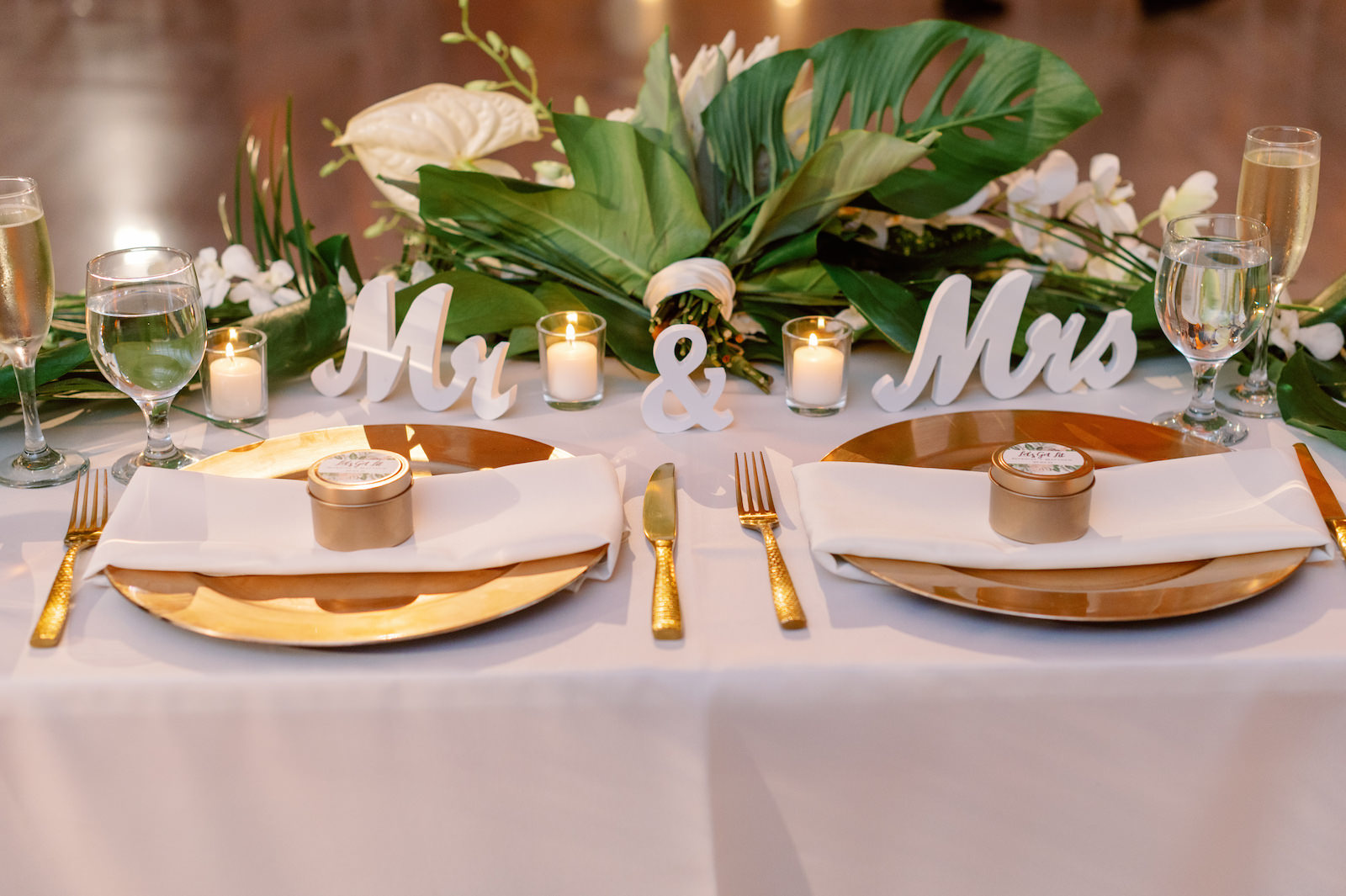 White and Green Modern Minimalist Tropical Wedding Reception Decor, Gold Chargers and Flatware, Wooden Mr and Mrs Laser Cut Words, Monstera Palm Leaves, White Anthurium, Orchids, King Protea Floral Arrangements | Tampa Bay Wedding Planner Taylored Affairs