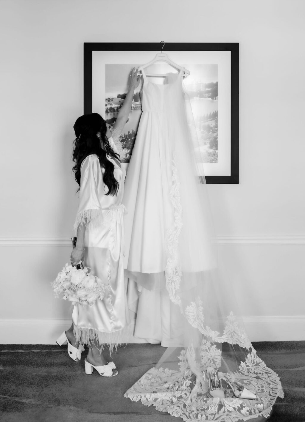 Classic Black and White Photo of Bride with Hanging A Line Wedding Dress and Full Length Veil Holding Floral Bouquet