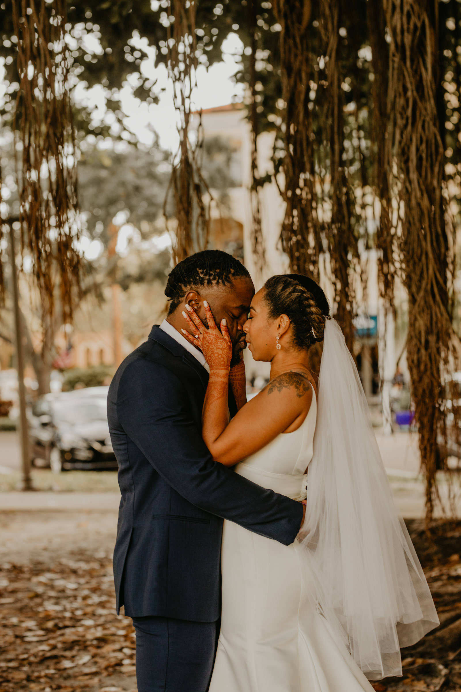 Intimate Elopement Wedding, Bride Wearing Fit and Flare Wedding Dress with Rhinestone Crystal Belt, Groom Wearing Navy Blue Suit and White Tie from Behind Under Banyan Trees, First Look Photo